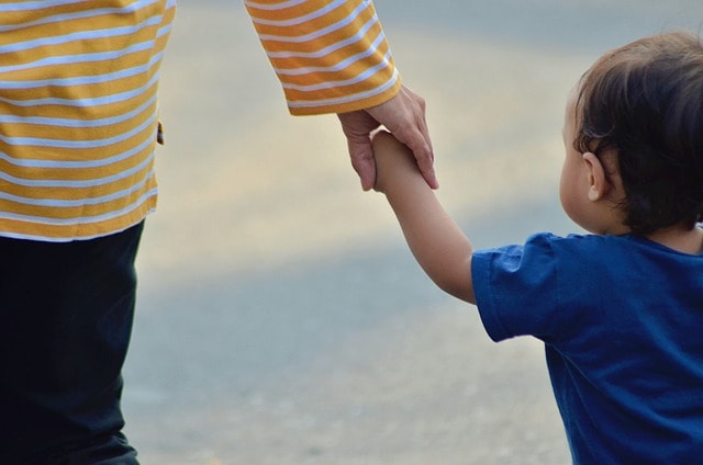 A child holds his mother's hand.