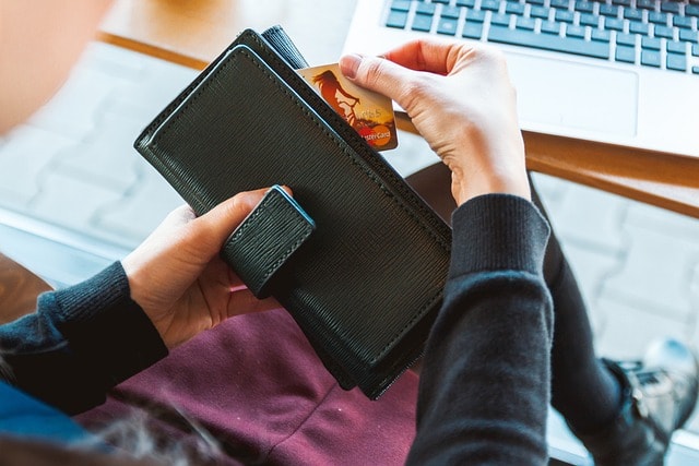 Close-up on a woman's hands as she pulls a credit card out of her wallet.