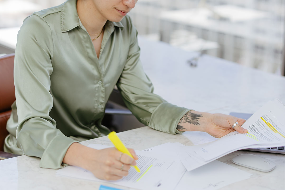 Person Holding highlighter Pen Writing on documents