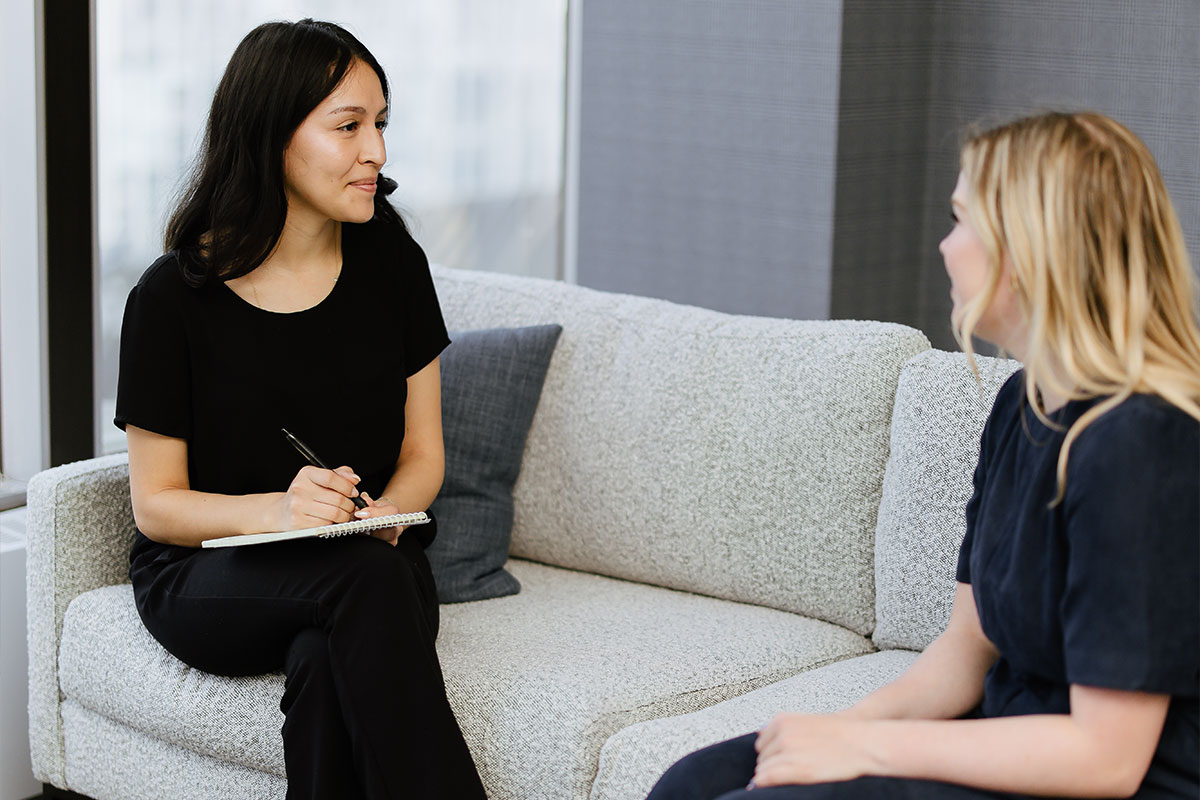 Woman Sitting on Chair Talking to another woman