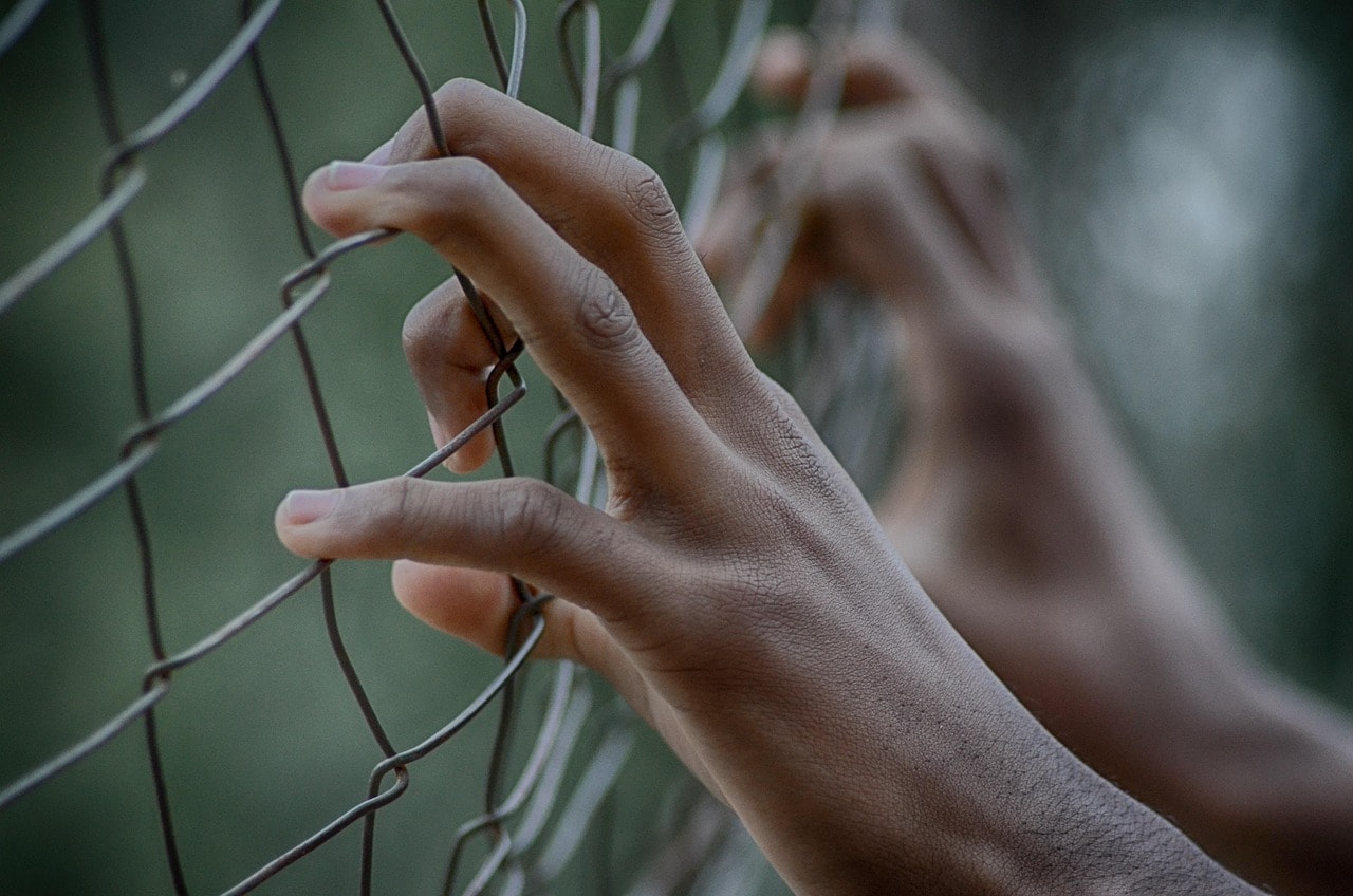 Young black person's hands on fence
