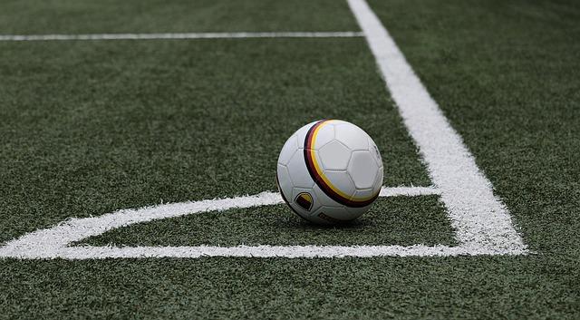 A soccer ball in the corner of a field.