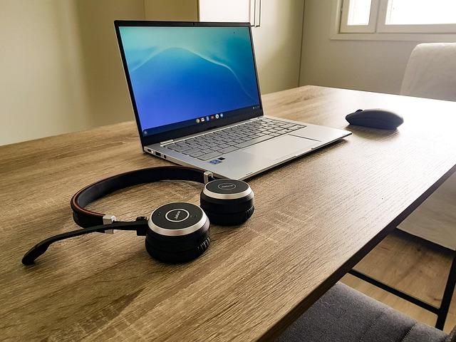 A computer, headset, and mouse on a plain brown desk.